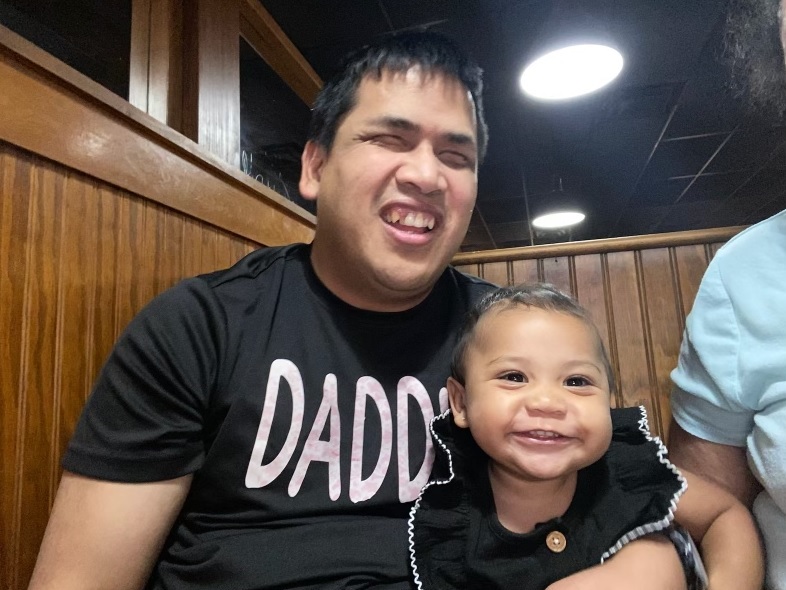Benjamin Wright, wearing a t-shirt that says "DADDY" poses with his young daughter.